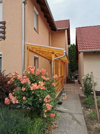 Fa előtető a ház oldalán, szemből, előtte virágzó rózsa
