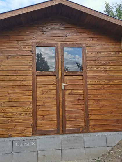Pácolt fa kerti faház üvegezett kétszárnyú ajtóval, közelről